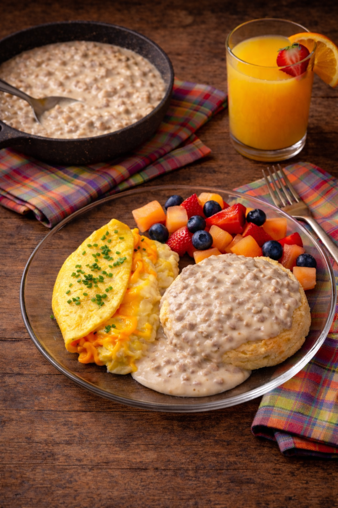 keto sausage gravy served with biscuit, fluffy omelet, and fresh fruit on a plate